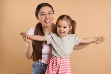 Photo of Portrait of happy mother and her cute little daughter on beige background