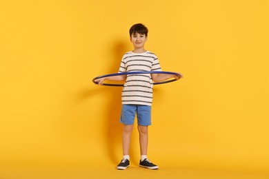 Photo of Boy exercising with hula hoop on yellow background