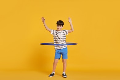 Photo of Boy exercising with hula hoop on yellow background