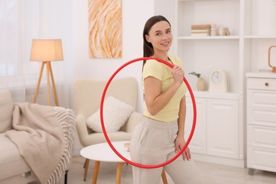 Smiling woman with hula hoop at home