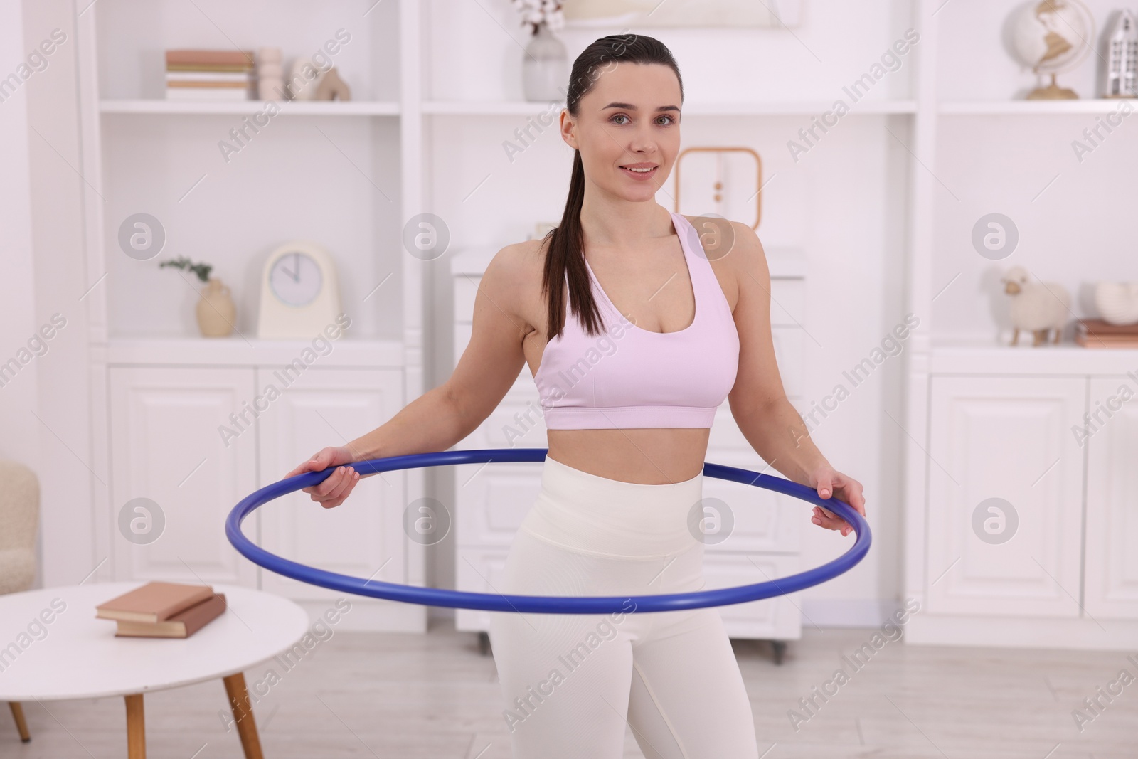 Photo of Smiling woman training with hula hoop at home