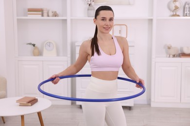 Photo of Smiling woman training with hula hoop at home