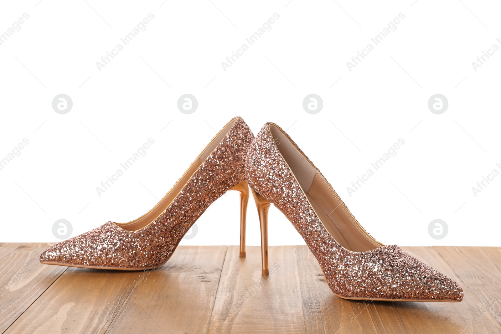 Photo of Beautiful high heeled shoes on wooden table against white background