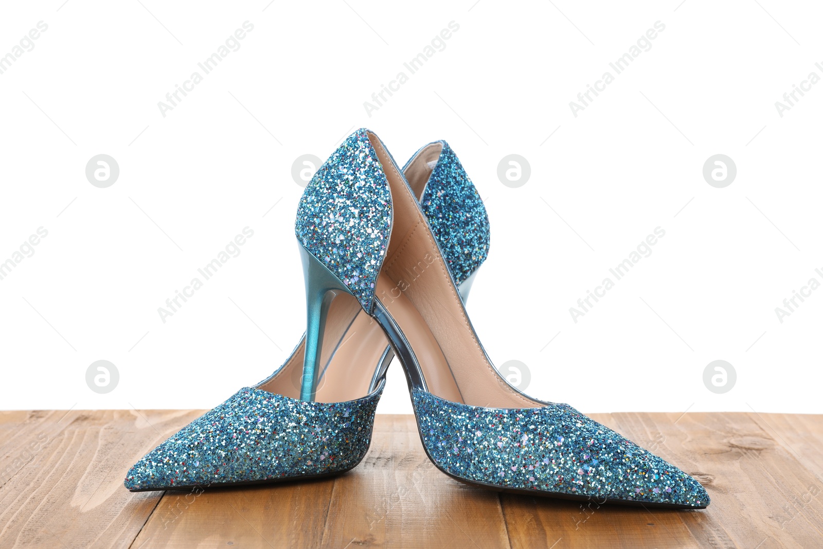 Photo of Beautiful high heeled shoes on wooden table against white background