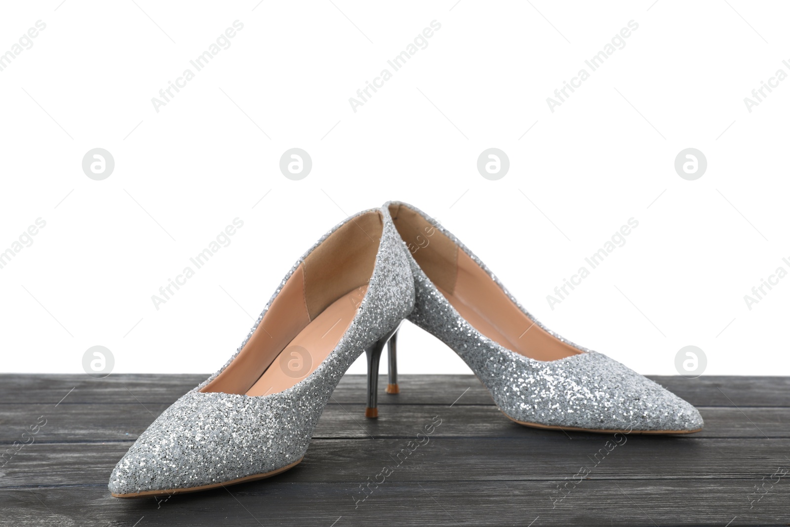 Photo of Beautiful high heeled shoes on black wooden table against white background