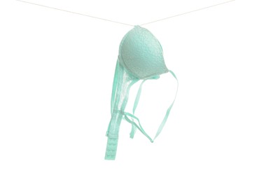 Beautiful turquoise bra hanging on rope against white background