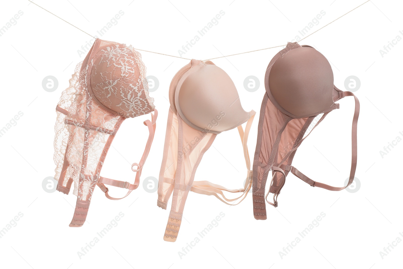 Photo of Beautiful bras hanging on rope against white background