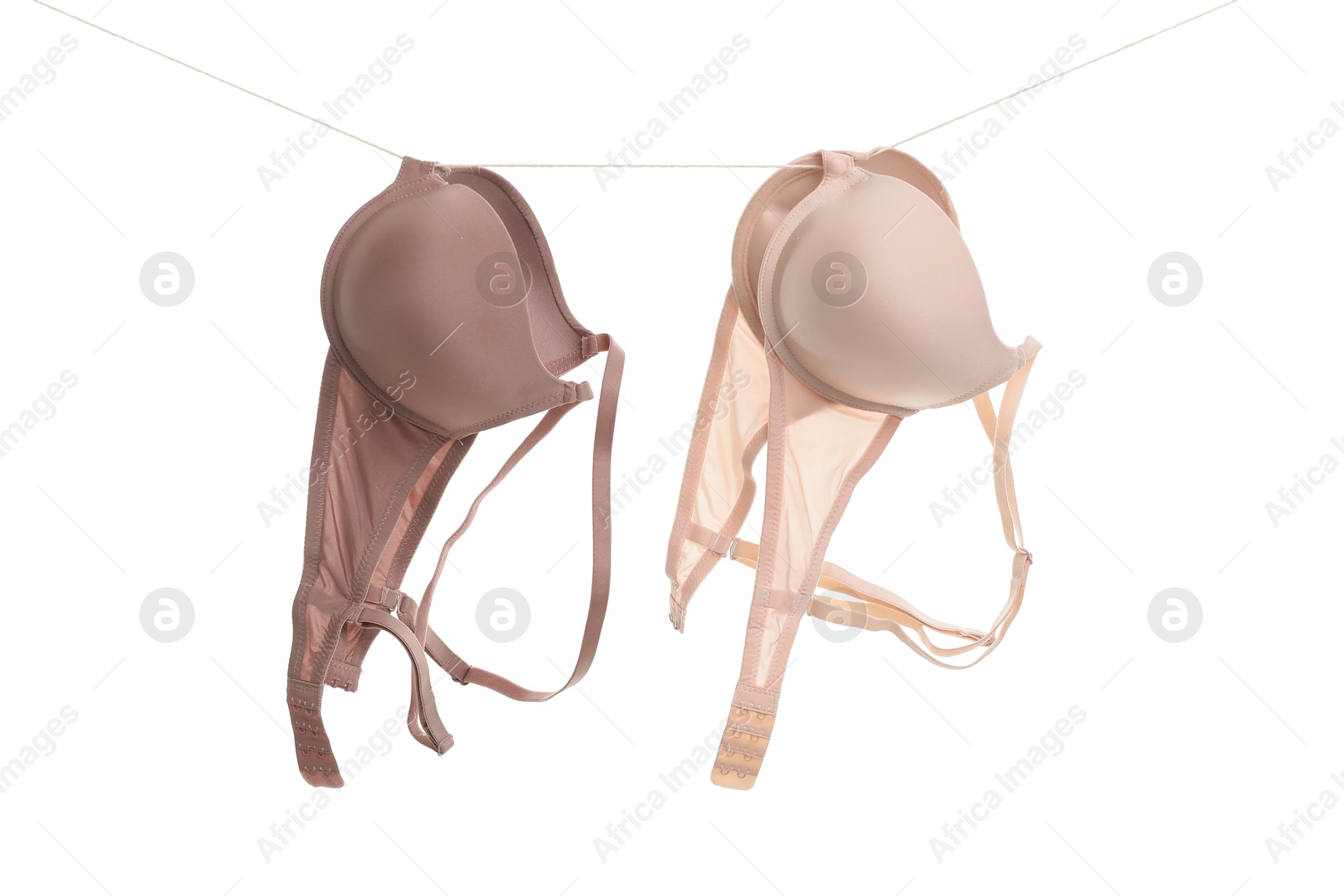 Photo of Beautiful bras hanging on rope against white background