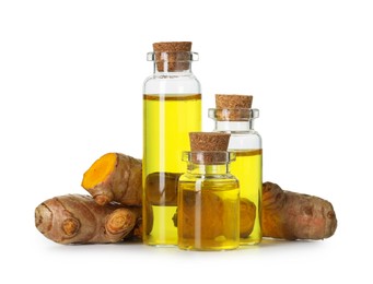 Photo of Bottles of turmeric essential oil and raw roots isolated on white