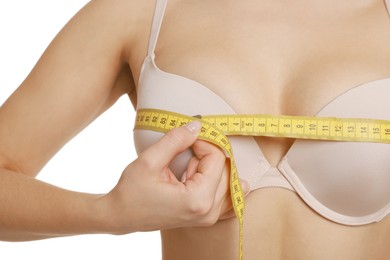 Woman in beautiful bra measuring breast circumference on white background, closeup