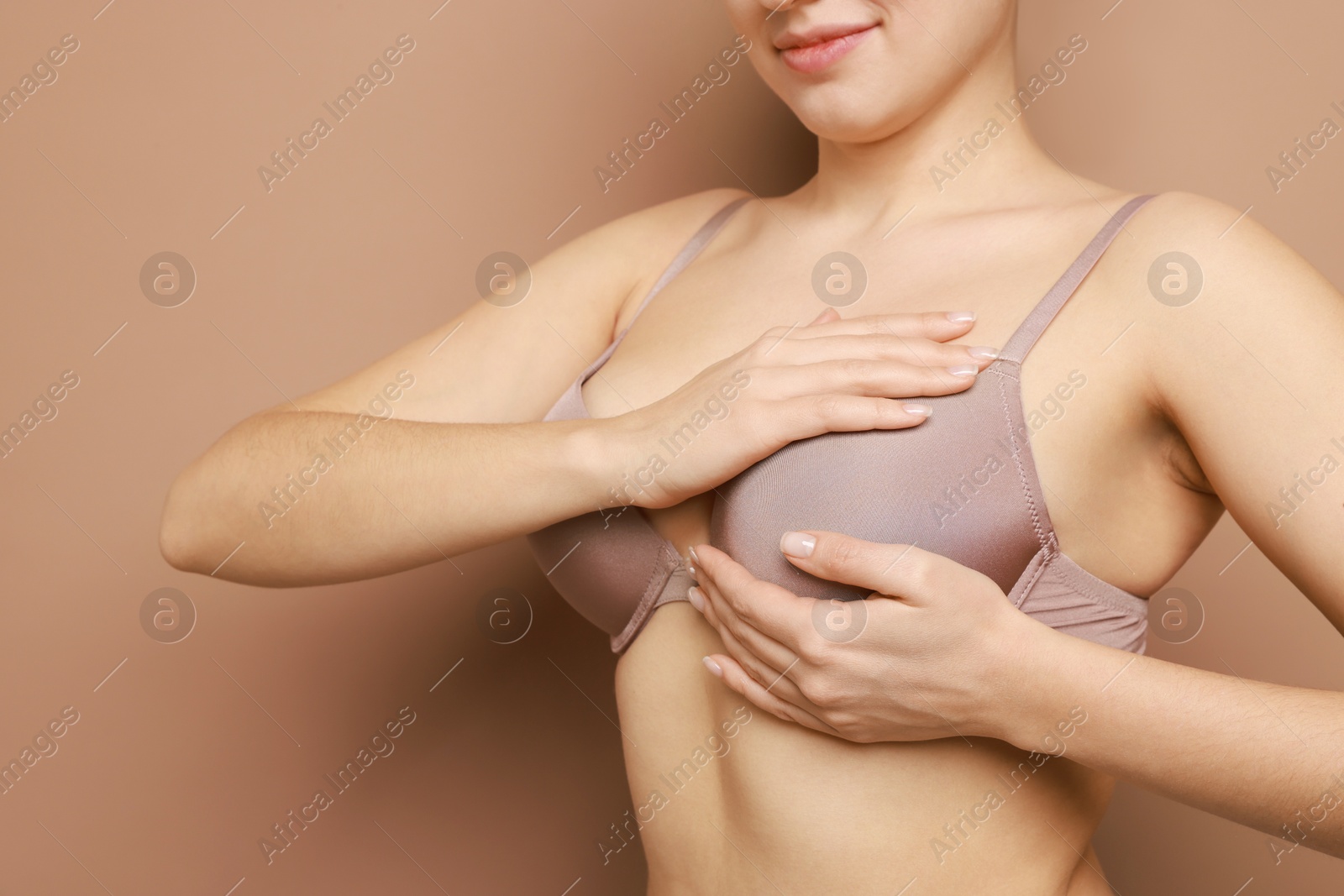 Photo of Woman wearing beautiful bra on beige background, closeup