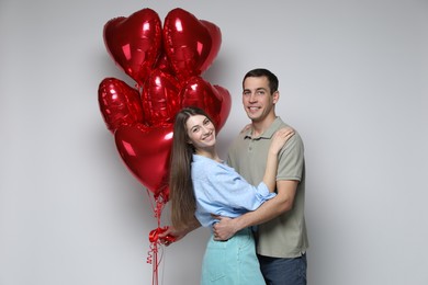 Photo of Lovely couple with heart shaped balloons on light background. Valentine's day celebration