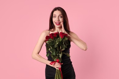 Photo of Happy Valentine's Day. Surprised woman with bouquet of roses on pink background