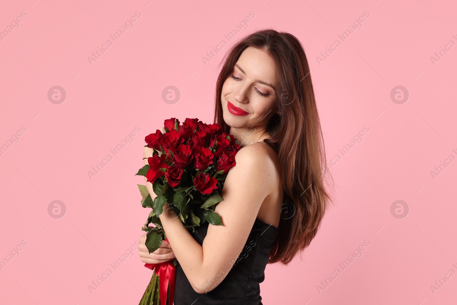 Photo of Happy Valentine's Day. Beautiful woman with bouquet of roses on pink background