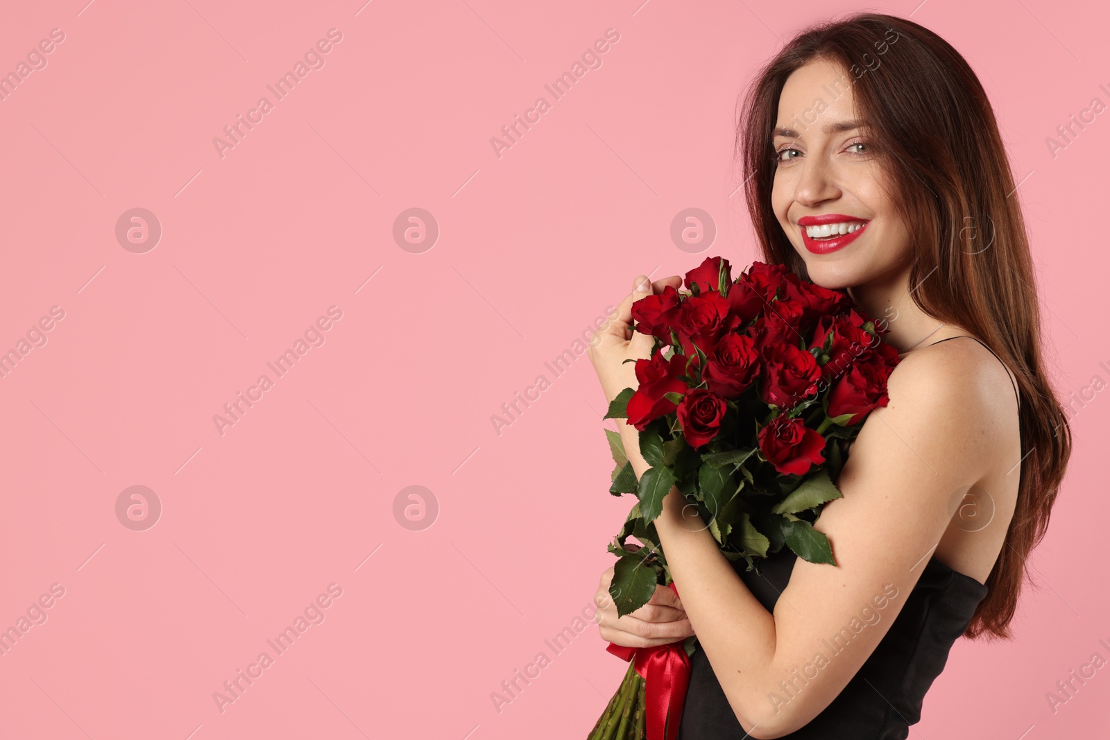 Photo of Happy Valentine's Day. Beautiful woman with bouquet of roses on pink background. Space for text