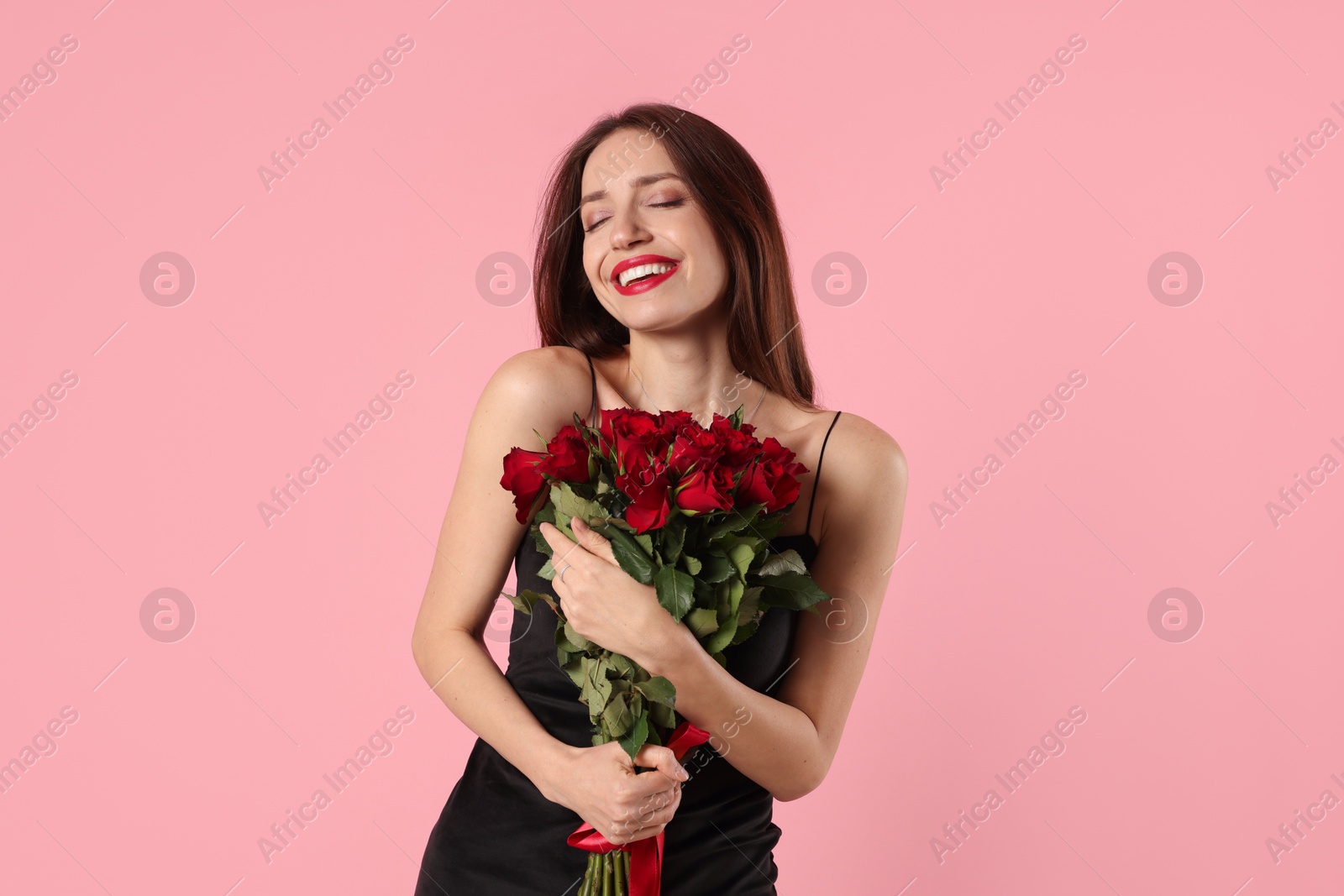 Photo of Happy Valentine's Day. Beautiful woman with bouquet of roses on pink background