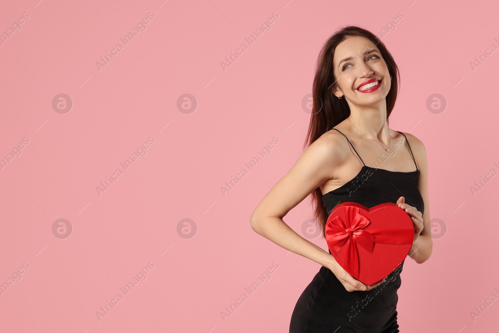 Photo of Happy Valentine's Day. Beautiful woman with heart shaped gift box on pink background. Space for text