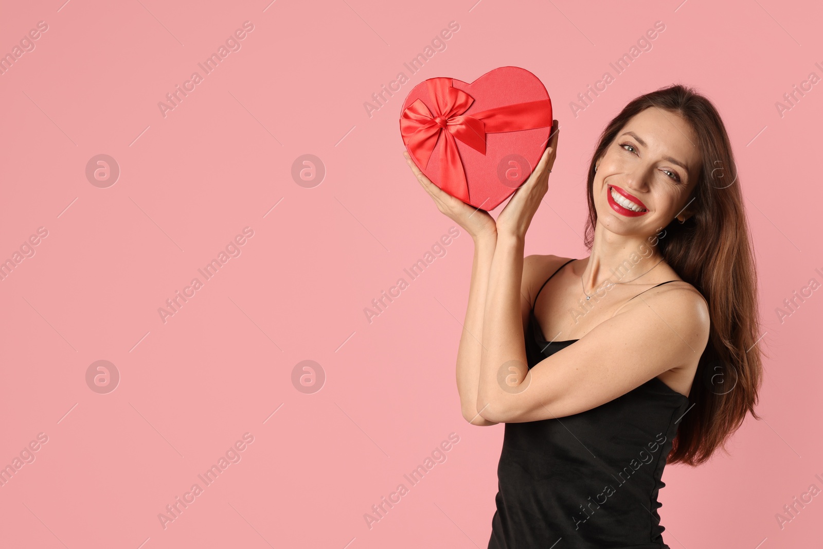 Photo of Happy Valentine's Day. Beautiful woman with heart shaped gift box on pink background. Space for text