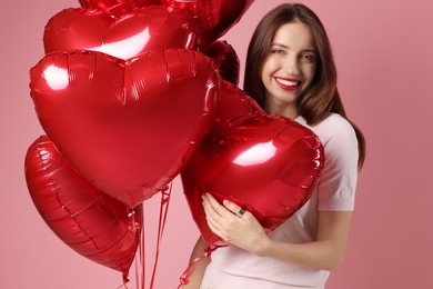 Photo of Happy Valentine's Day. Beautiful woman with heart shaped balloons on pink background