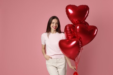 Photo of Happy Valentine's Day. Beautiful woman with heart shaped balloons on pink background