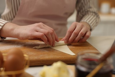 Photo of Woman rolling croissant from fresh dough at table, closeup