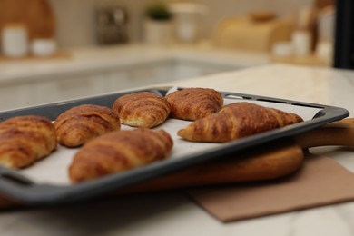 Photo of Freshly baked croissants on light table indoors, closeup