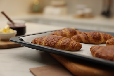 Photo of Freshly baked croissants on light table indoors, closeup