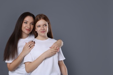 Photo of Family portrait of beautiful mother with teenage daughter on grey background, space for text