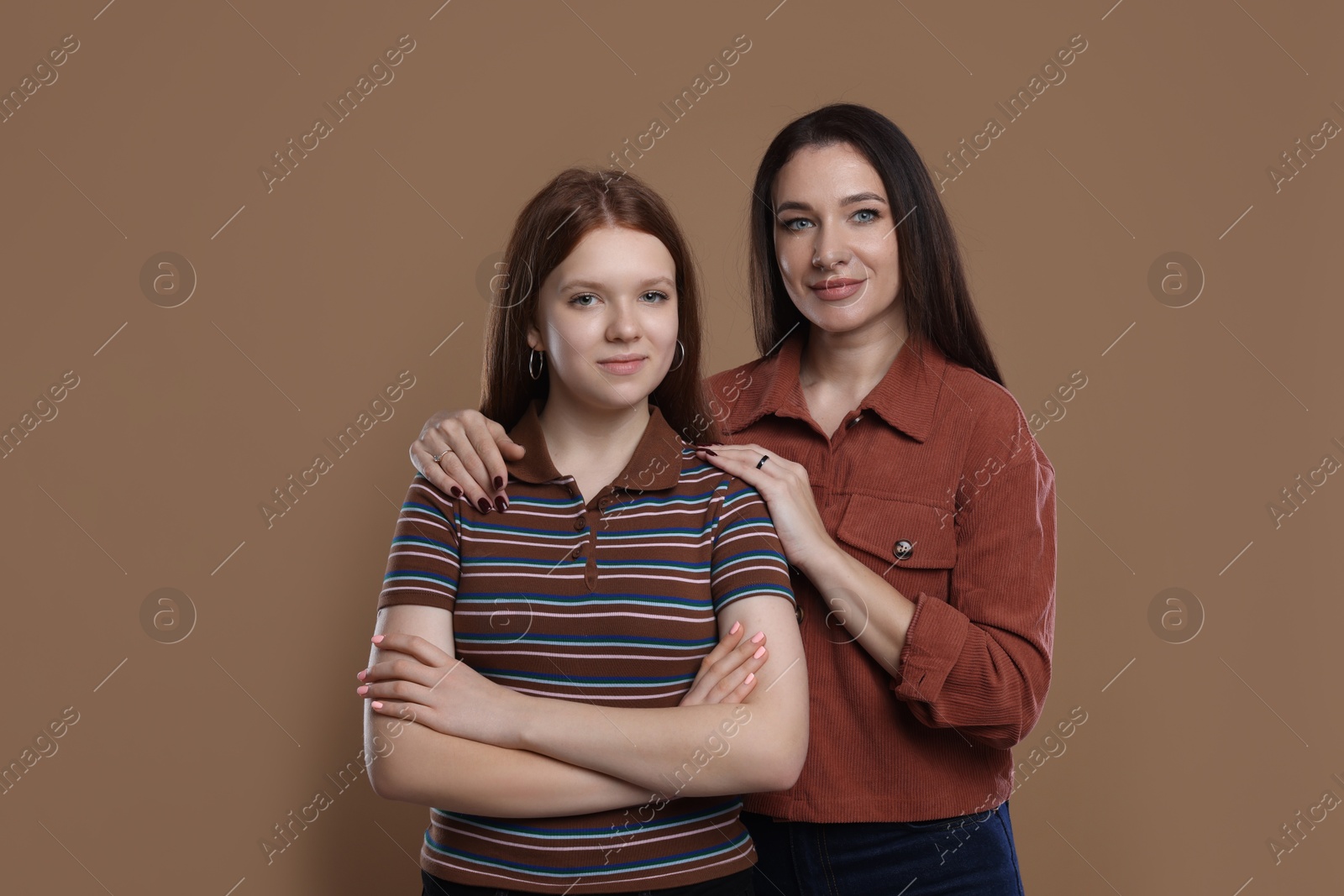 Photo of Portrait of beautiful mother with teenage daughter on dark beige background