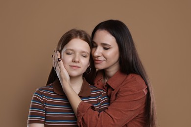 Photo of Portrait of beautiful mother with teenage daughter on dark beige background