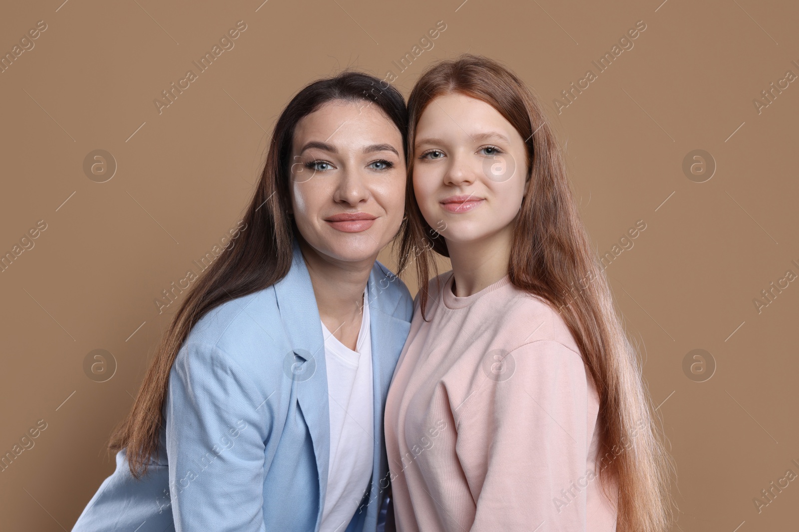 Photo of Portrait of beautiful mother with teenage daughter on dark beige background