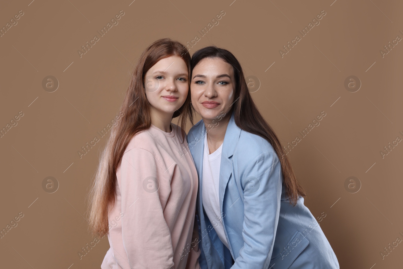 Photo of Portrait of beautiful mother with teenage daughter on dark beige background