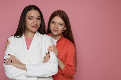 Photo of Portrait of beautiful mother with teenage daughter on pink background, space for text