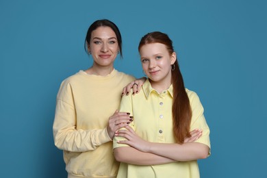 Photo of Portrait of beautiful mother with teenage daughter on light blue background