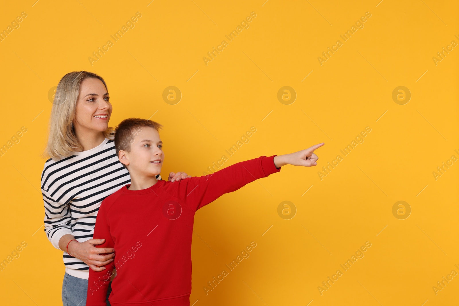 Photo of Son showing his mother something on orange background. Space for text