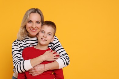 Photo of Mother and son hugging on orange background. Space for text