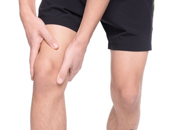 Young man suffering from pain in knee on white background, closeup