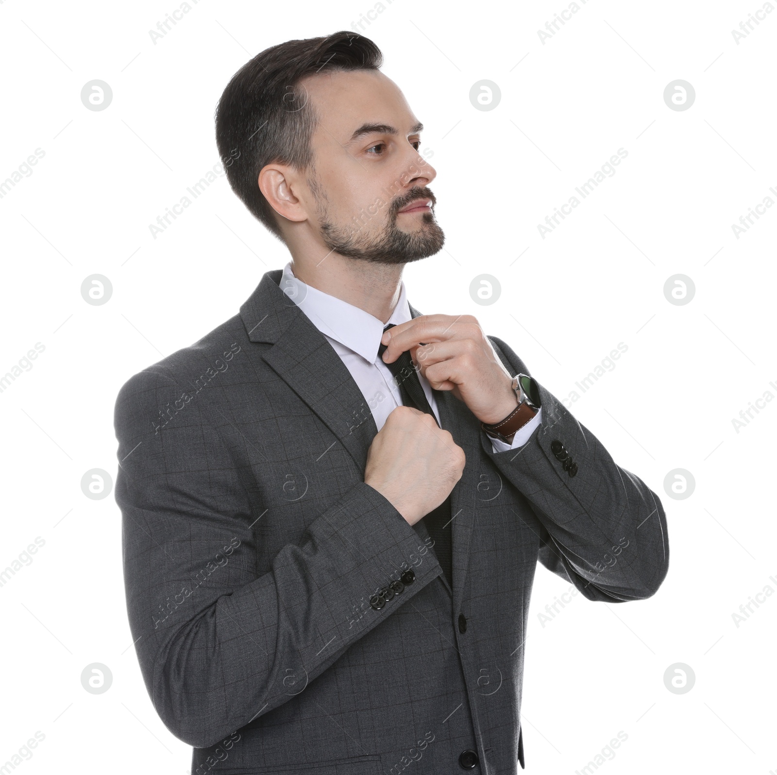 Photo of Confident man in classic suit straightening tie on white background