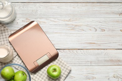 Photo of Electronic kitchen scale and products on white wooden table, flat lay. Space for text