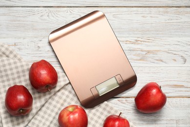 Photo of Electronic kitchen scale and apples on white wooden table, flat lay