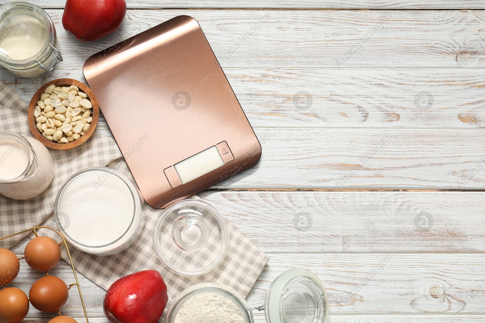 Photo of Electronic kitchen scale and products on white wooden table, flat lay. Space for text