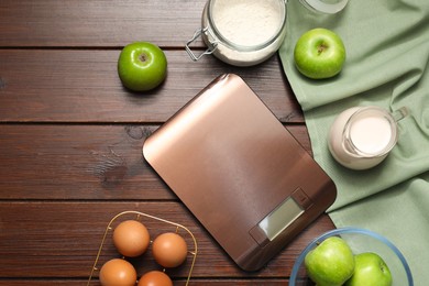 Photo of Electronic kitchen scale and products on wooden table, flat lay