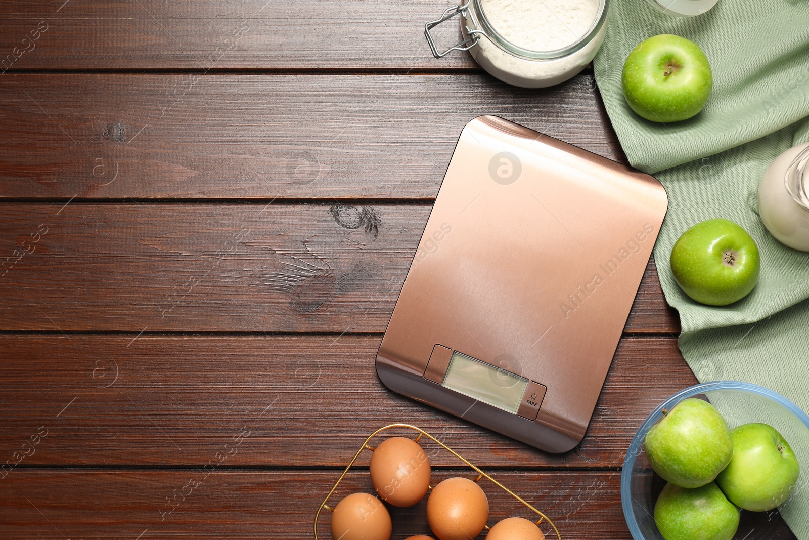 Photo of Electronic kitchen scale and products on wooden table, flat lay. Space for text