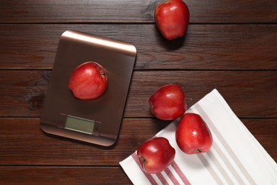 Photo of Electronic kitchen scale and apples on wooden table, flat lay