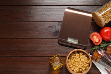 Electronic kitchen scale and products on wooden table, flat lay. Space for text