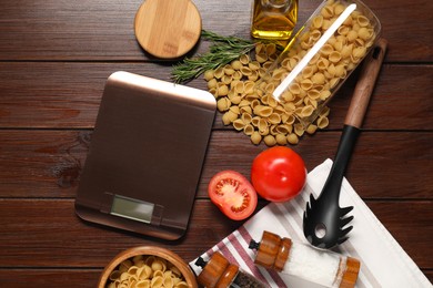 Photo of Electronic kitchen scale and products on wooden table, flat lay