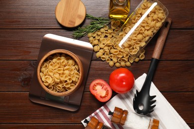 Photo of Electronic kitchen scale and products on wooden table, flat lay