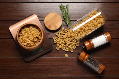 Photo of Electronic kitchen scale and products on wooden table, flat lay