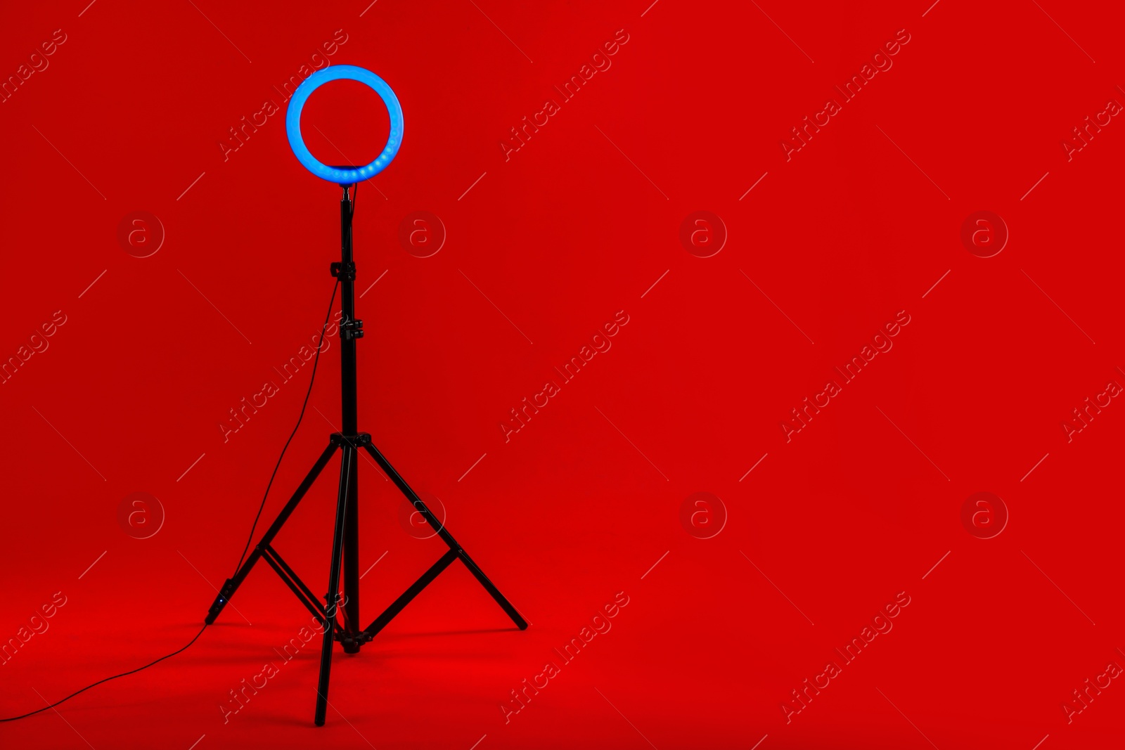 Photo of Ring lamp on stand against red background, space for text