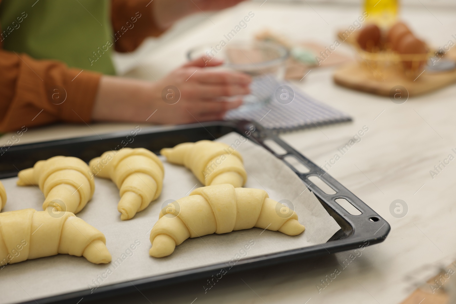 Photo of Woman making croissants at white marble table, selective focus